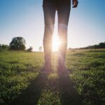 Sunlight Protection - person in black pants standing on green grass field during daytime