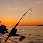 Recreational Gear - black fishing rod and body of water during golden hour