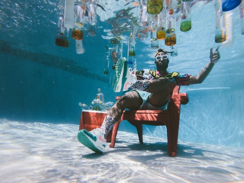Pool Supplies - man sitting on chair underwater with floating bottles