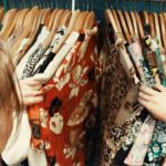 Vintage Clothing - person holding assorted clothes in wooden hanger