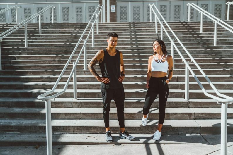 Workout Clothes - woman in black tank top and black pants standing on gray concrete stairs